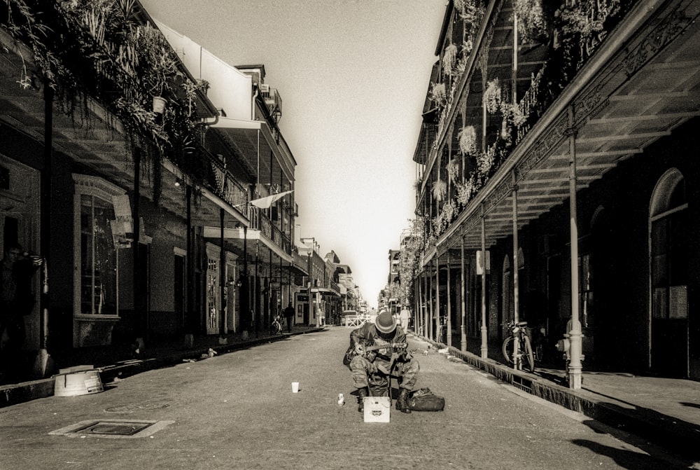 grayscale photo of people walking on street in between buildings