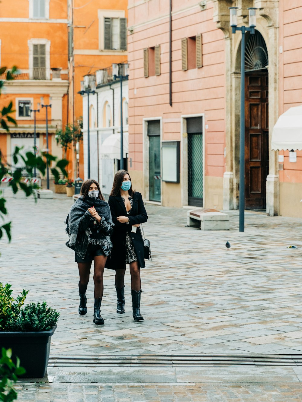 woman in black coat walking on sidewalk during daytime