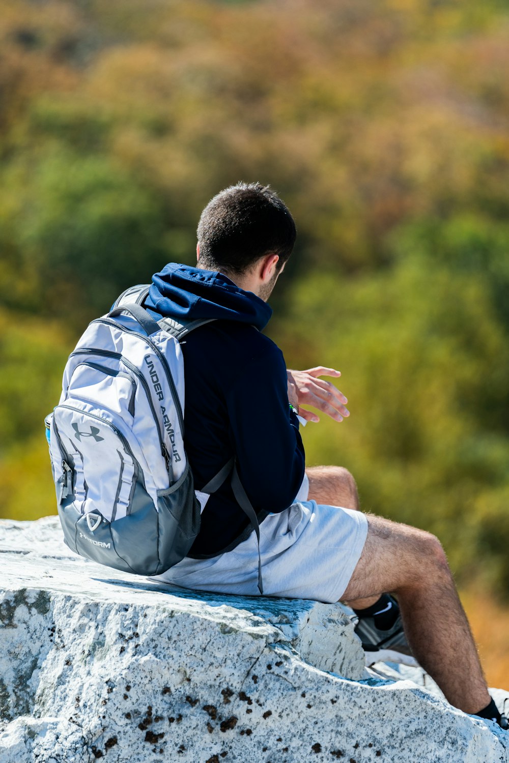 man in black jacket sitting on rock during daytime