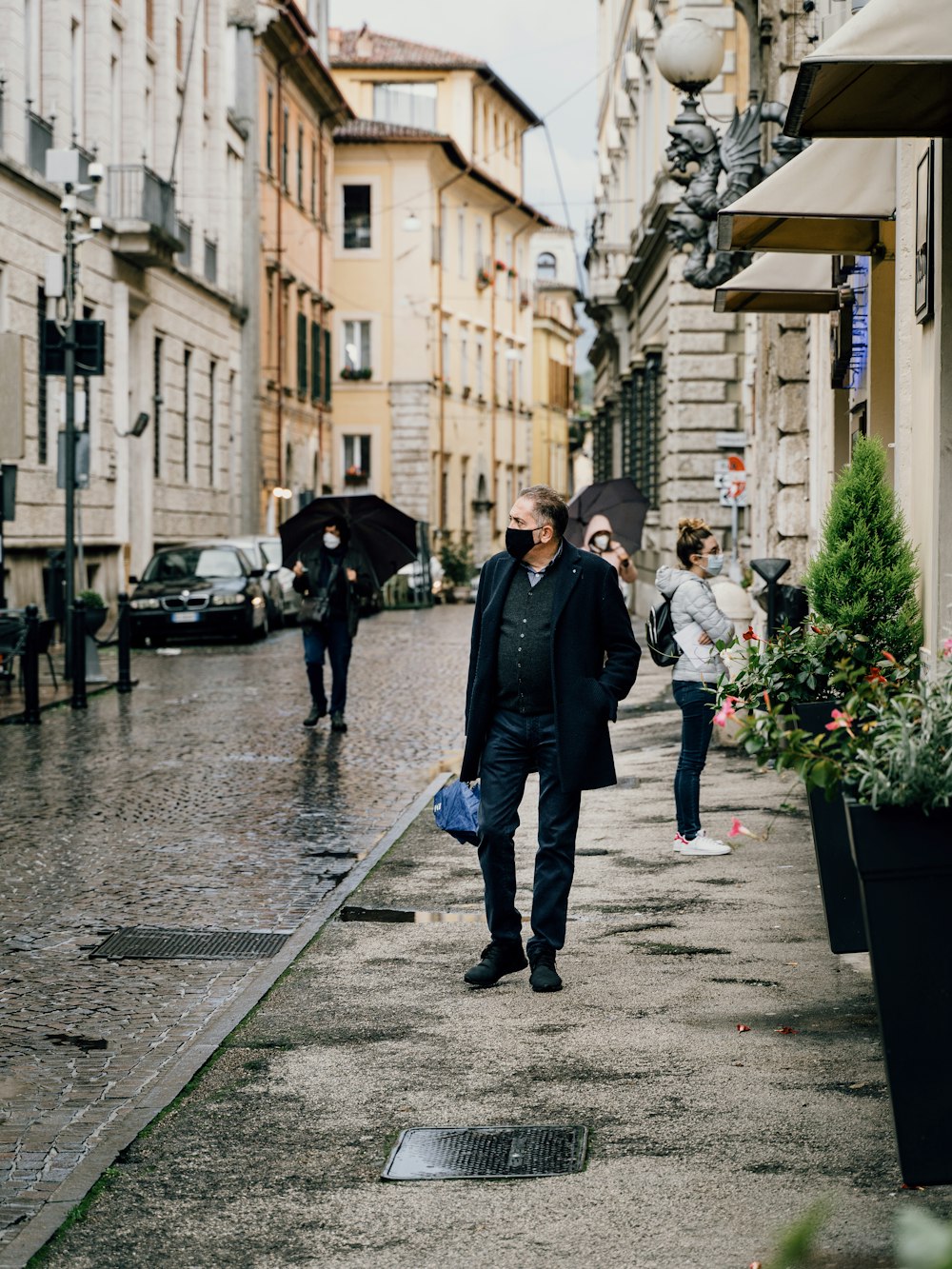 man in black jacket walking on sidewalk during daytime