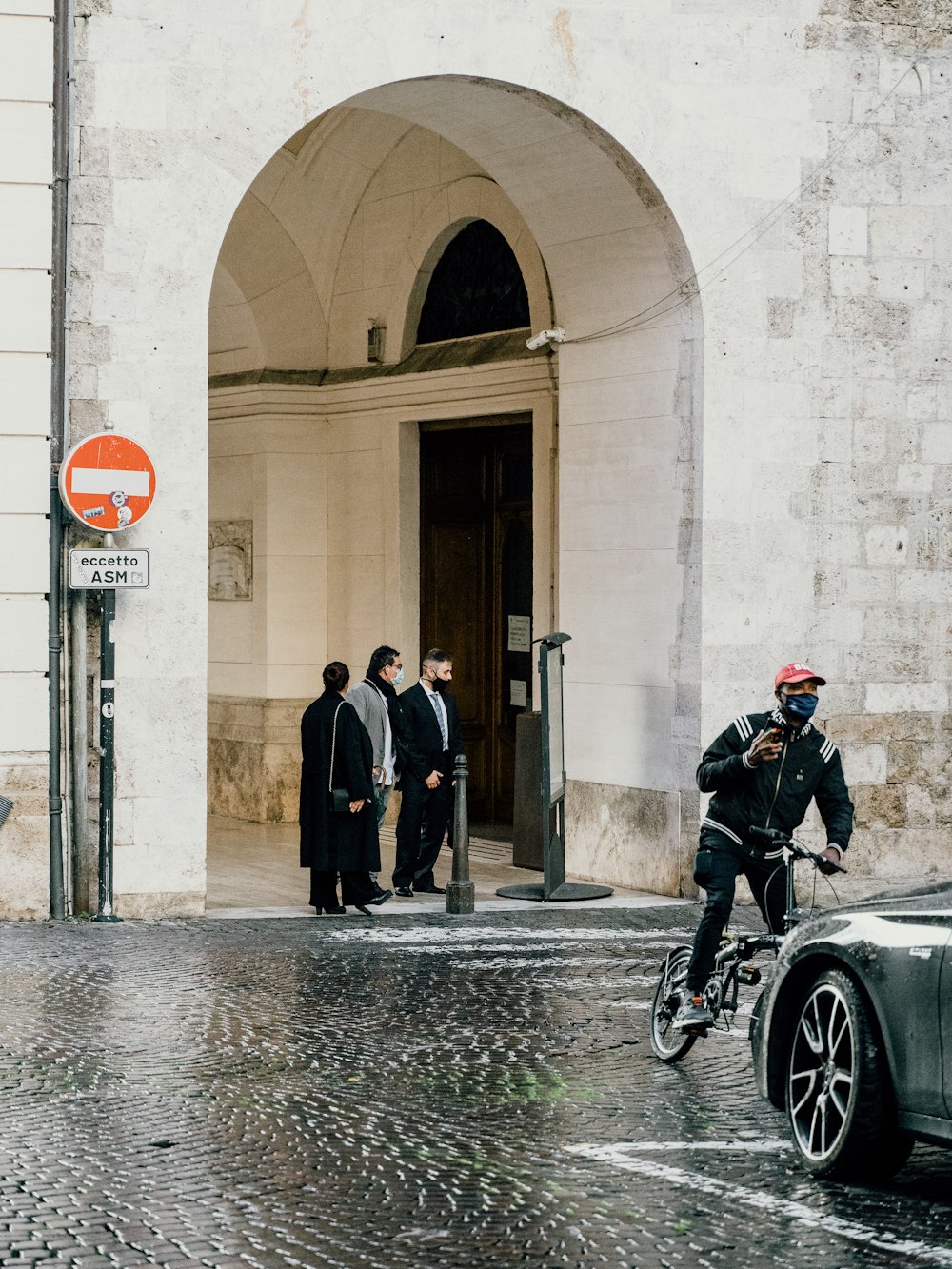 homme en manteau noir marchant sur le trottoir pendant la journée