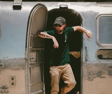 man in black t-shirt and brown pants sitting on gray bus