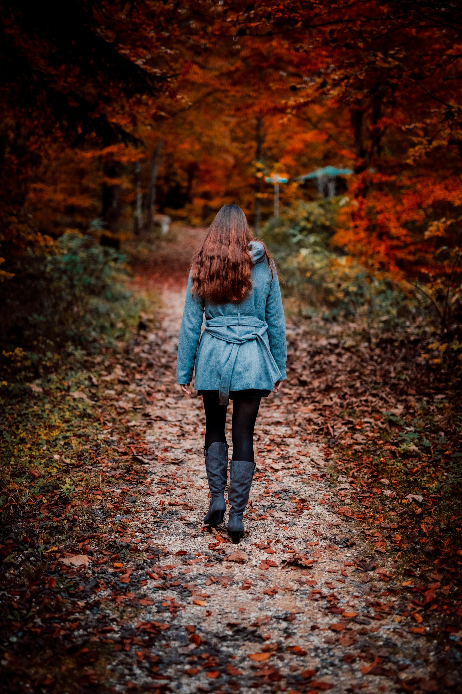 A woman walking on a quiet path in autumn light, unhurried.