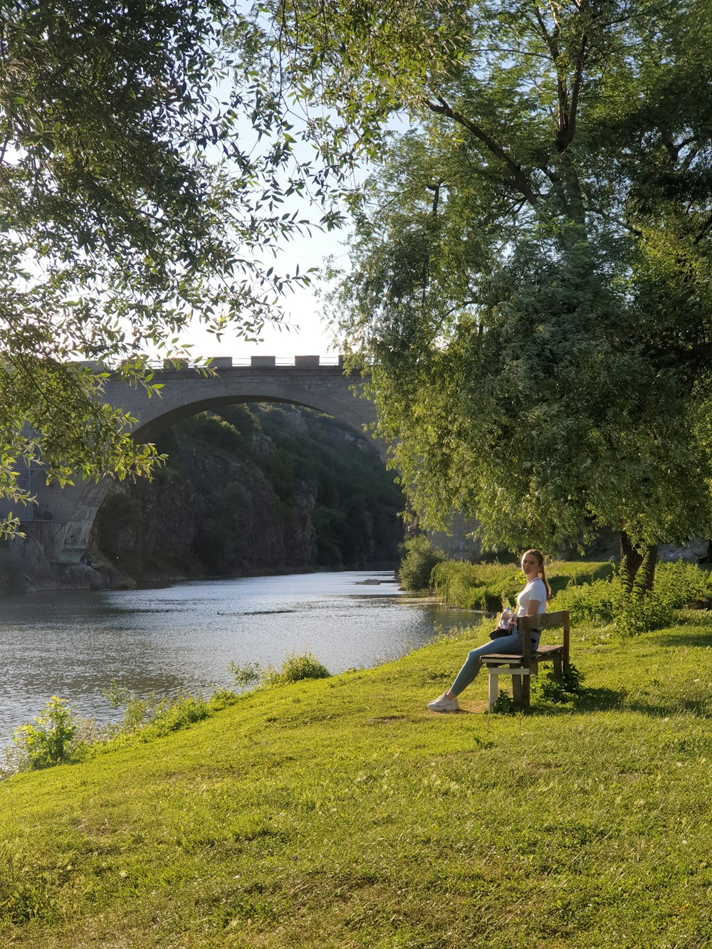 man and woman sitting on green grass near river during daytime