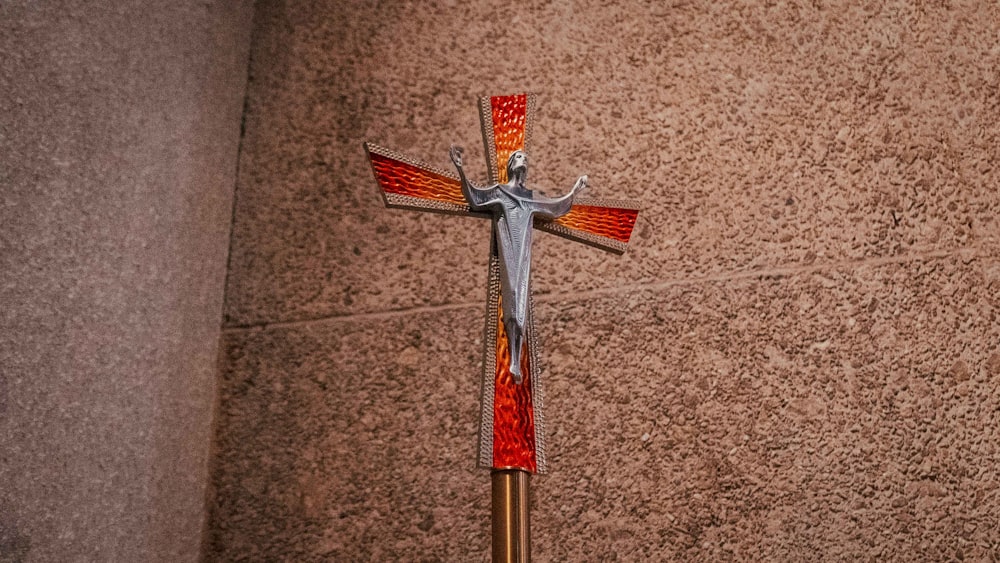 cruz prateada e vermelha no chão marrom