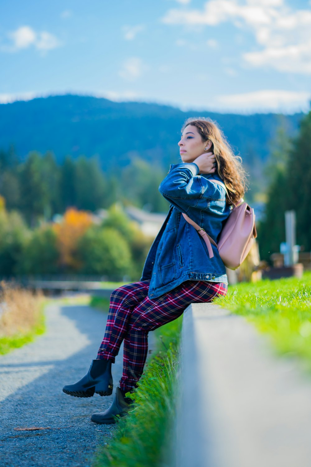 woman in blue scarf and red plaid long sleeve shirt standing on road during daytime