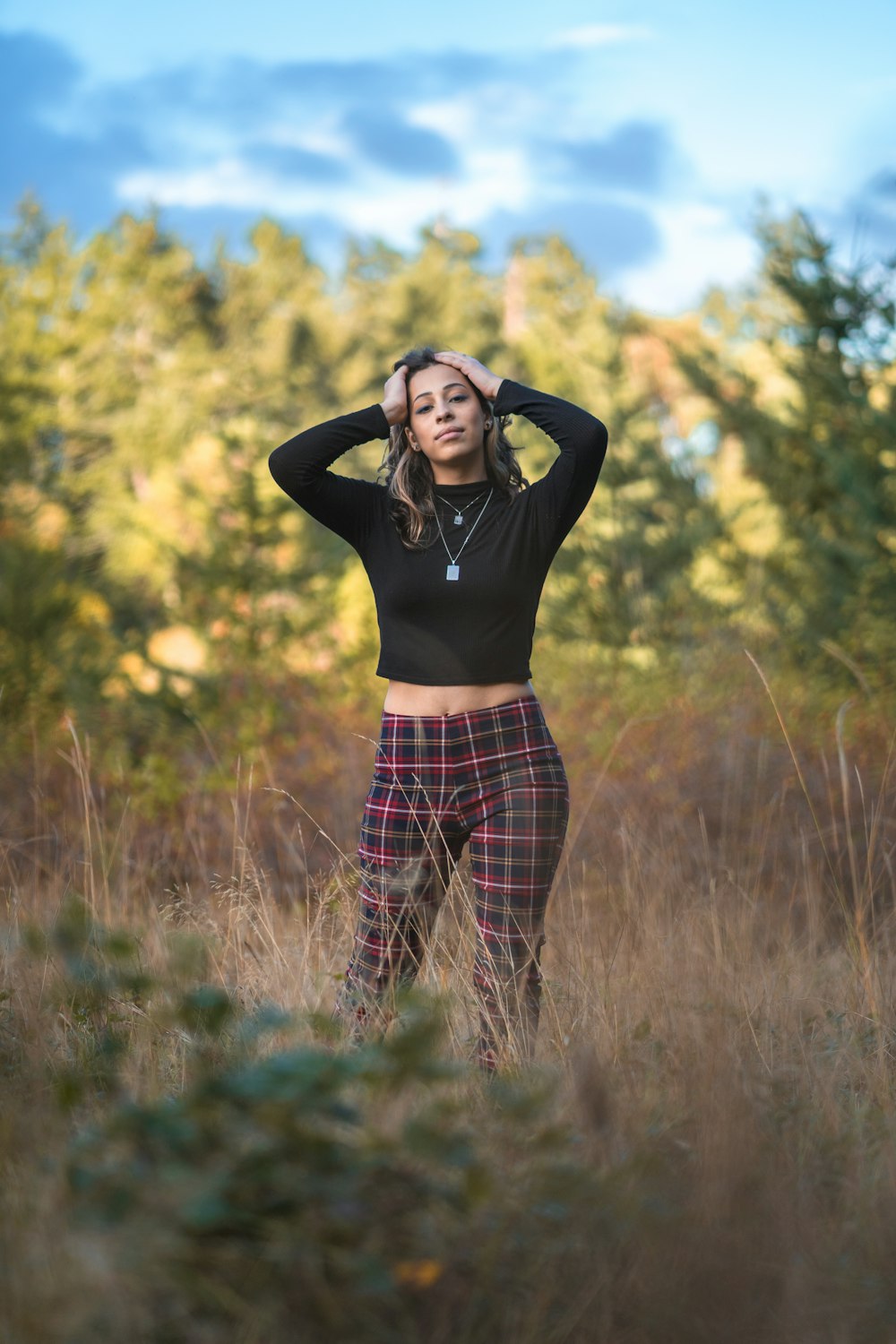 woman in black long sleeve shirt and red and black plaid pants standing on green grass