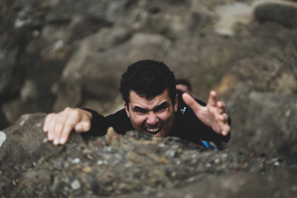 uomo in t-shirt girocollo nera sdraiato su roccia grigia