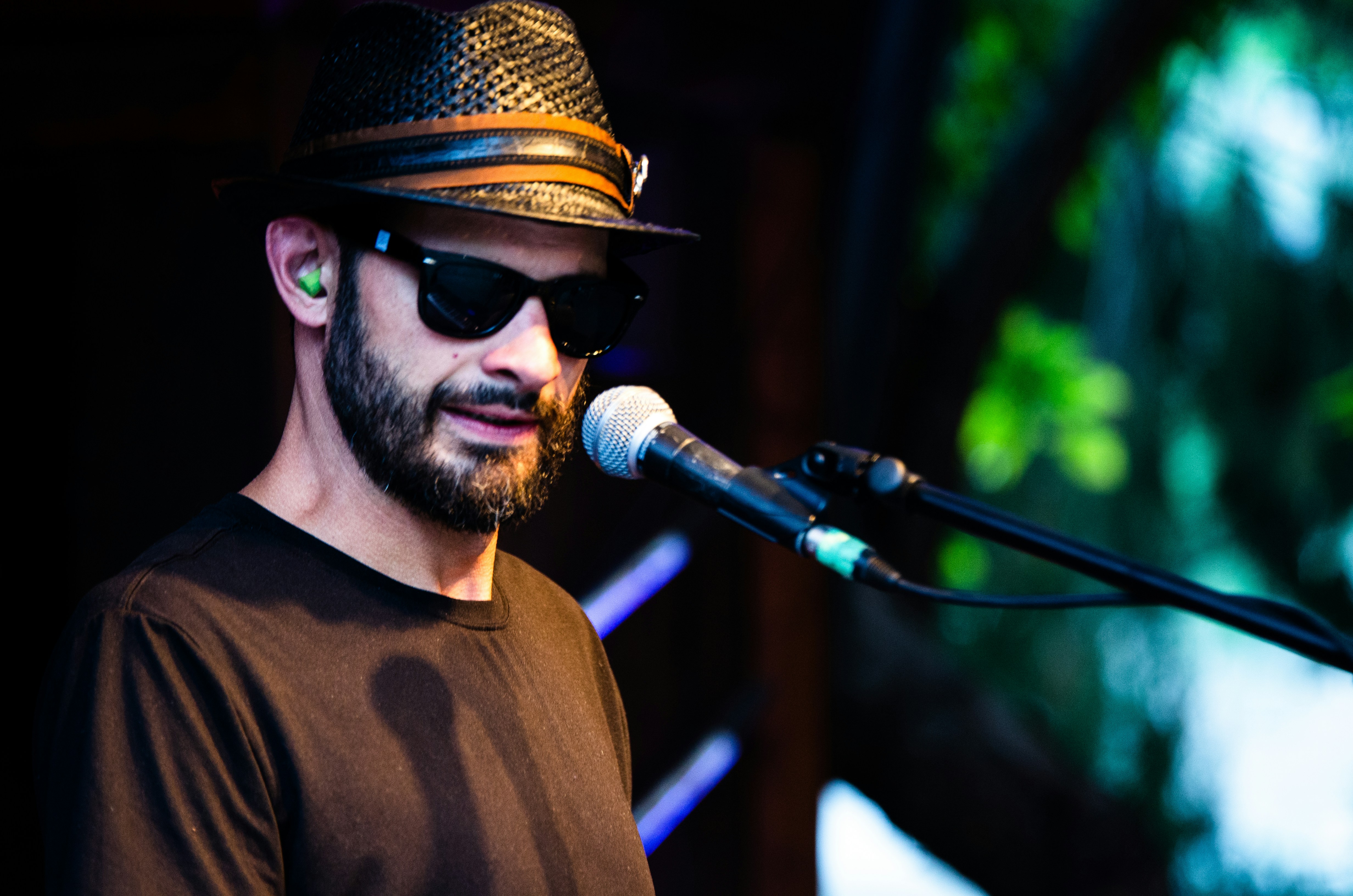 man in brown crew neck shirt wearing black hat singing