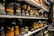 Shelves filled with rows of various pairs of boots and shoes are seen, each with labels and tags attached for identification. The footwear appears to be organized meticulously, possibly indicating a storage area or inventory space. The room lighting creates a warm tone, highlighting the textures and materials of the shoes.