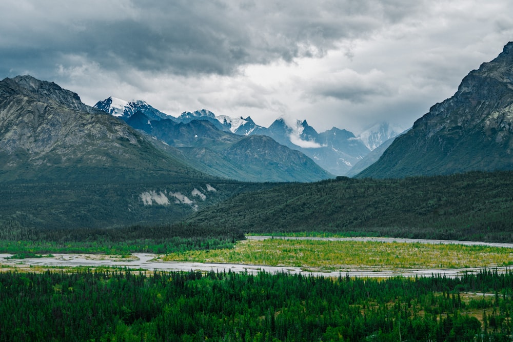 green grass field near mountain under cloudy sky during daytime