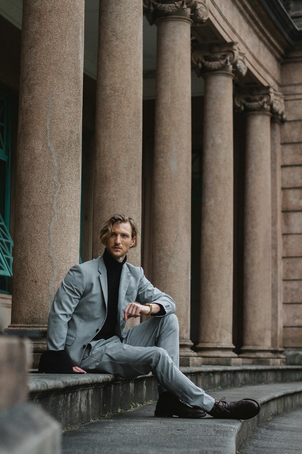 man in gray suit sitting on gray concrete bench