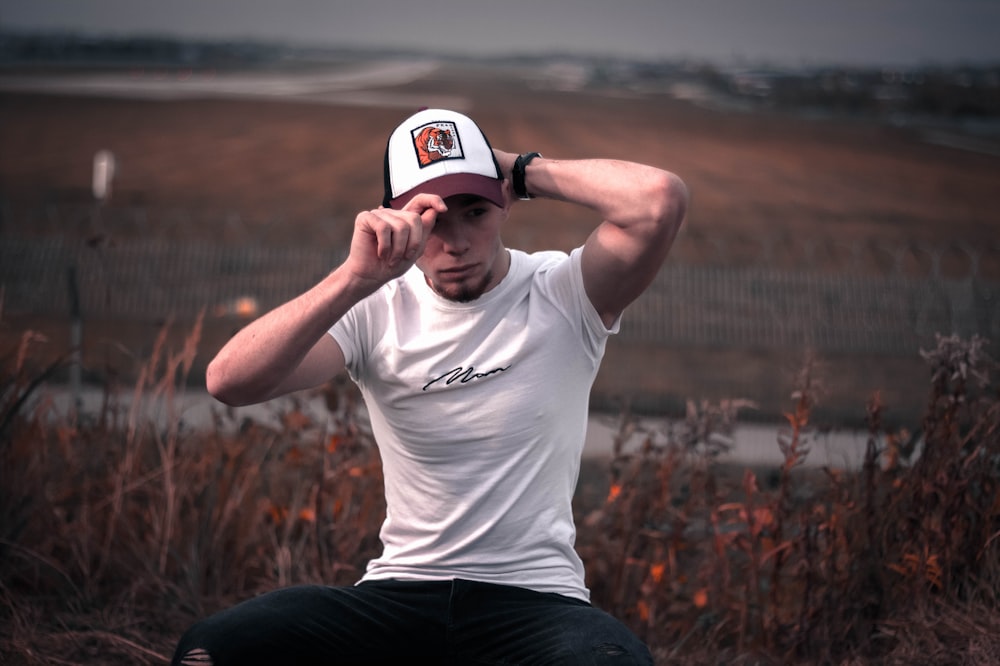 man in white crew neck t-shirt and black pants wearing white cap