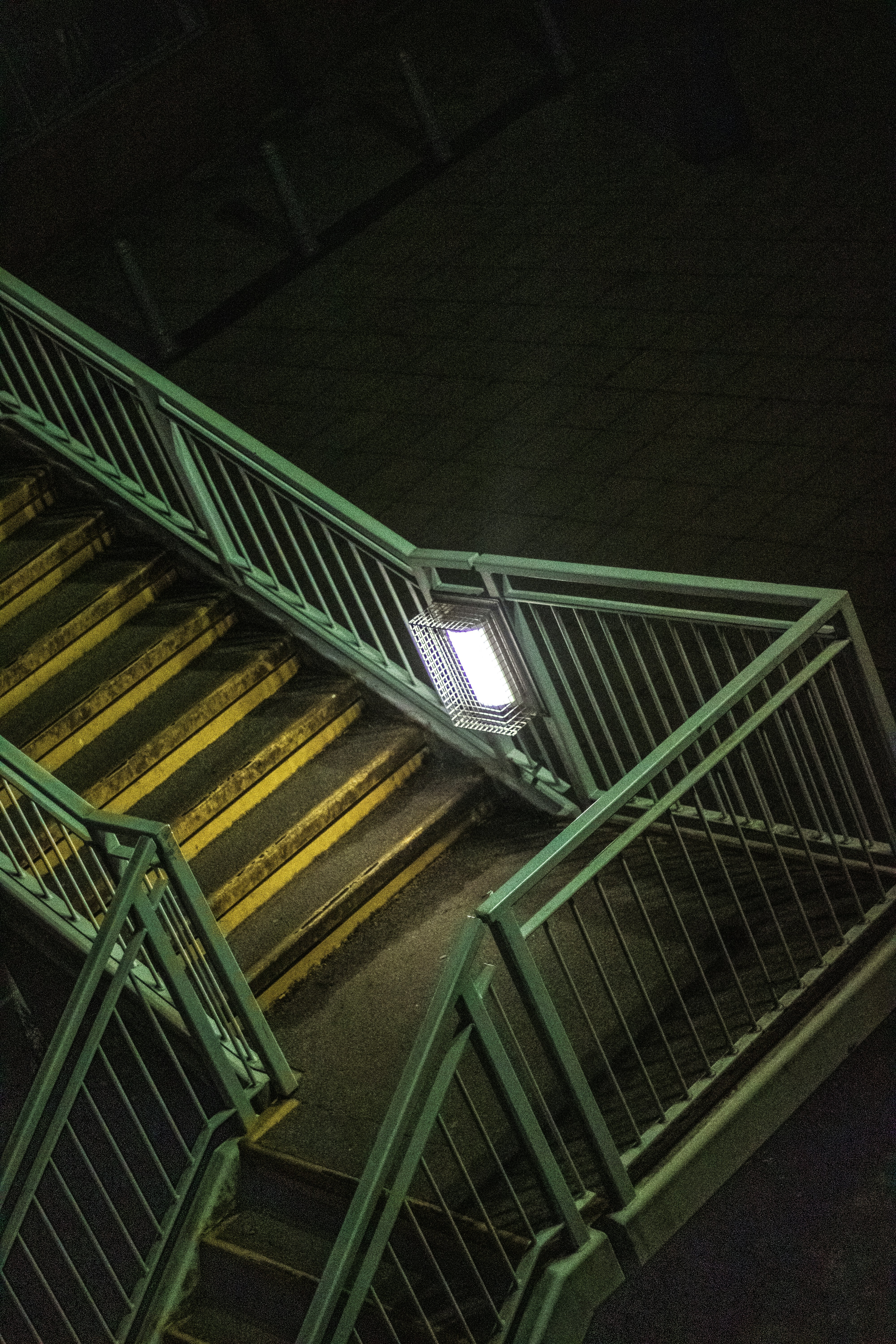 green metal staircase with yellow metal railings