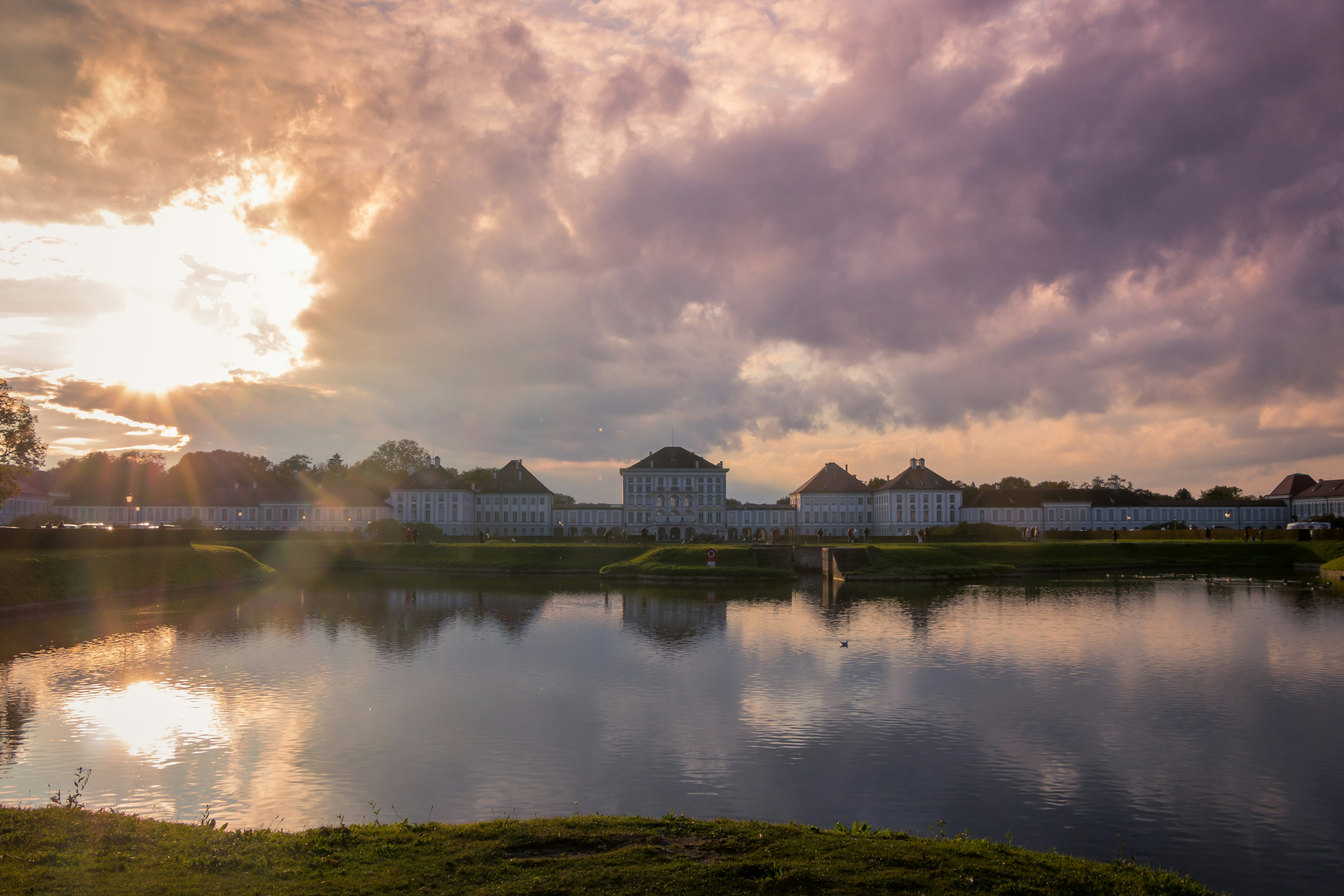 body of water near green grass field and trees under cloudy sky during daytime