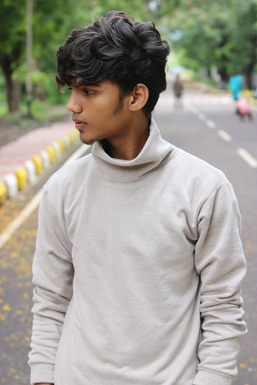 man in gray sweater standing on road during daytime