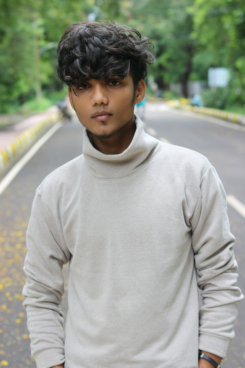 man in white turtleneck sweater standing on road during daytime