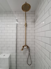 gold shower head on white ceramic bathtub