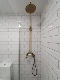 gold shower head on white ceramic bathtub