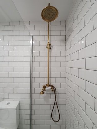 gold shower head on white ceramic bathtub
