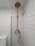 A bathroom with white subway tiles covering the walls, a vintage-style brass shower fixture that includes a showerhead at the top and a faucet below, and a modern toilet partially visible to the left. The overall look is clean and minimalistic.
