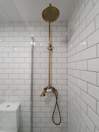 gold shower head on white ceramic bathtub