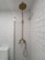 A bathroom with white subway tiles covering the walls, a vintage-style brass shower fixture that includes a showerhead at the top and a faucet below, and a modern toilet partially visible to the left. The overall look is clean and minimalistic.