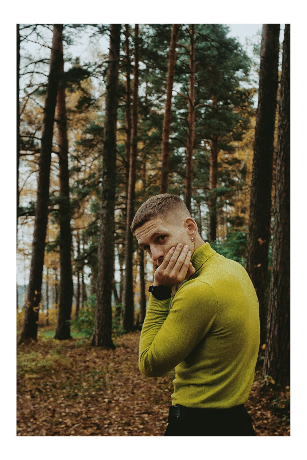 man in green sweater standing in forest during daytime