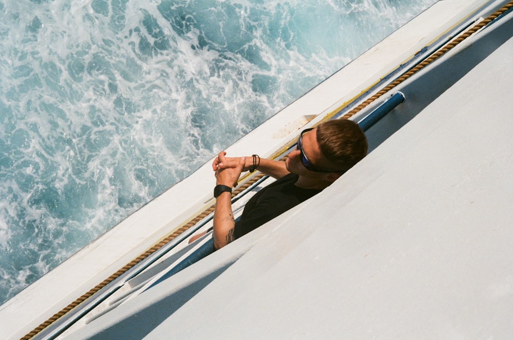 Femme en haut de bikini noir et lunettes de soleil noires assise sur un bateau blanc pendant la journée