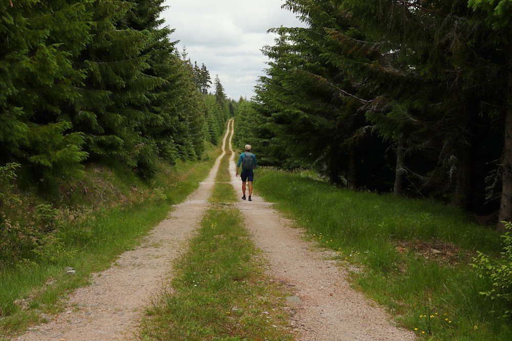 man in blue shirt walking on dirt road