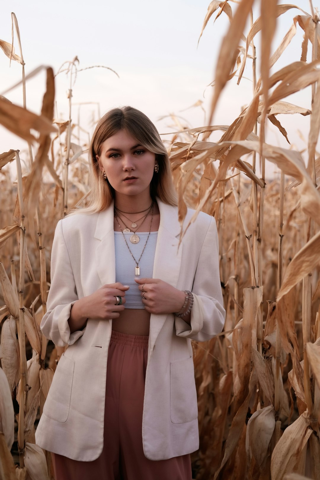 woman in white blazer standing near brown plants