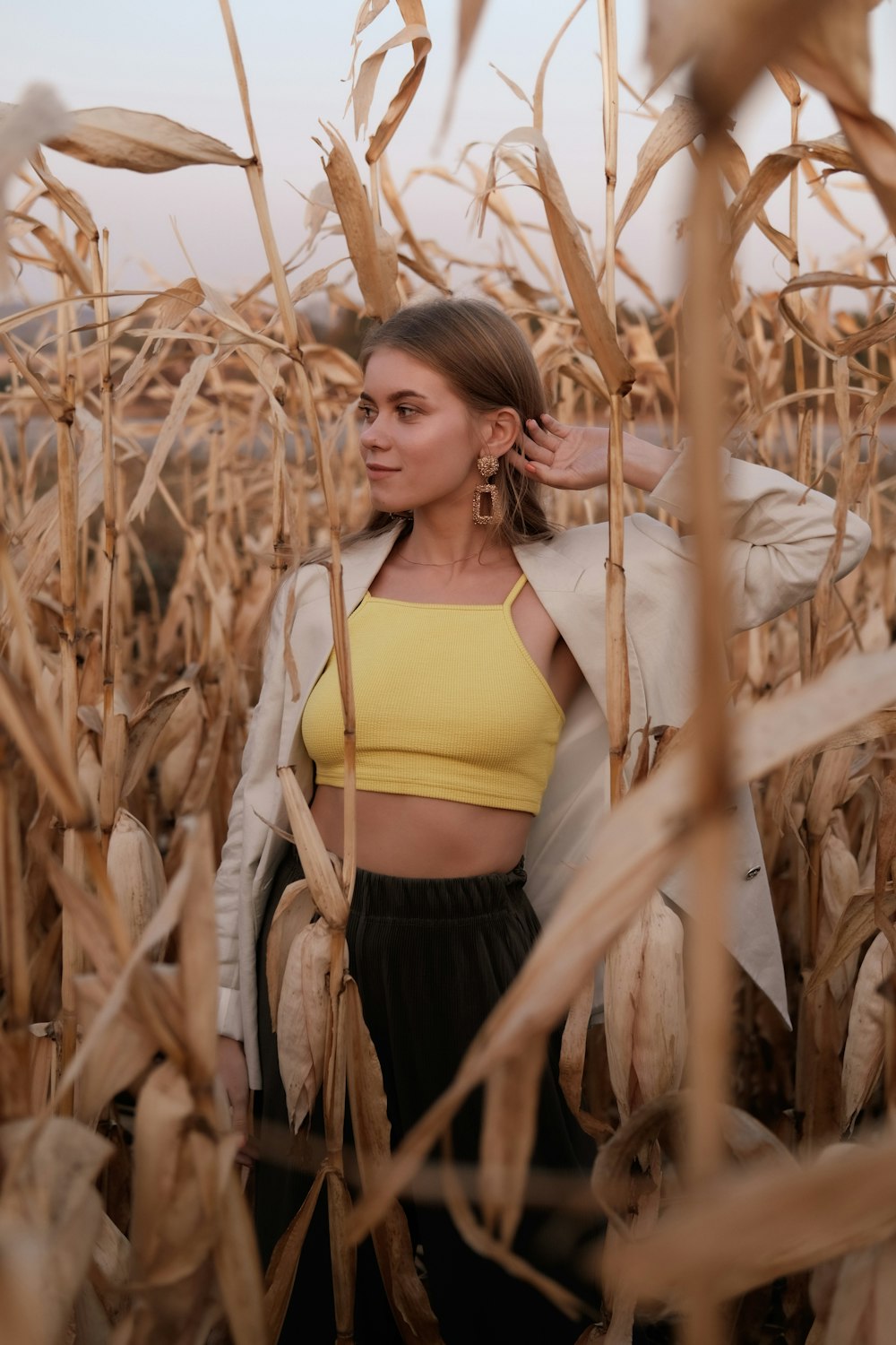woman in yellow brassiere and black skirt standing on corn field during daytime
