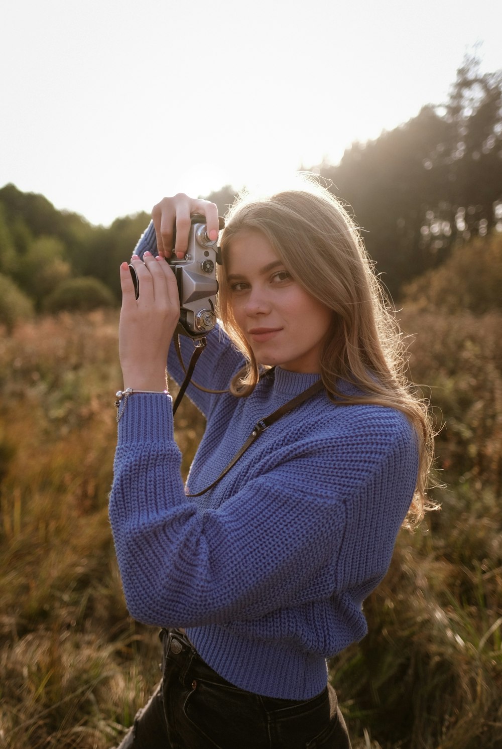 woman in blue sweater holding white smartphone