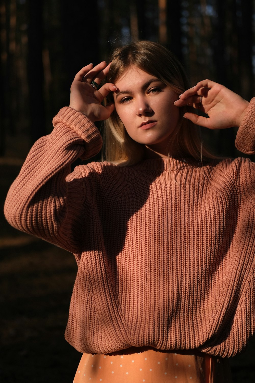 woman in brown sweater holding her hair