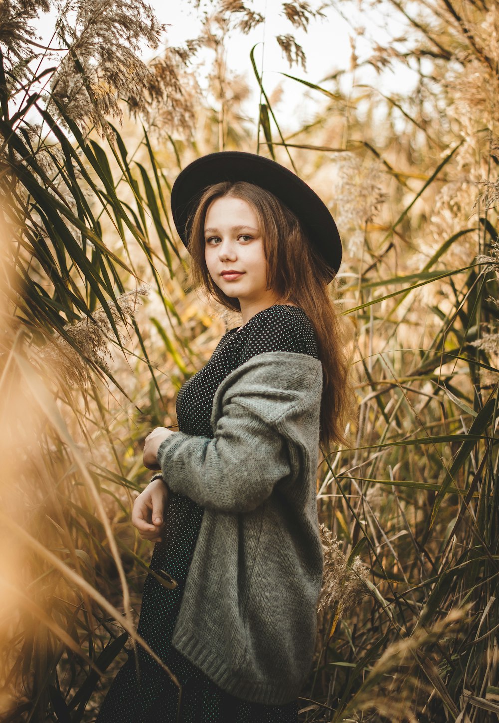 woman in black and white striped long sleeve shirt and black hat standing on brown grass