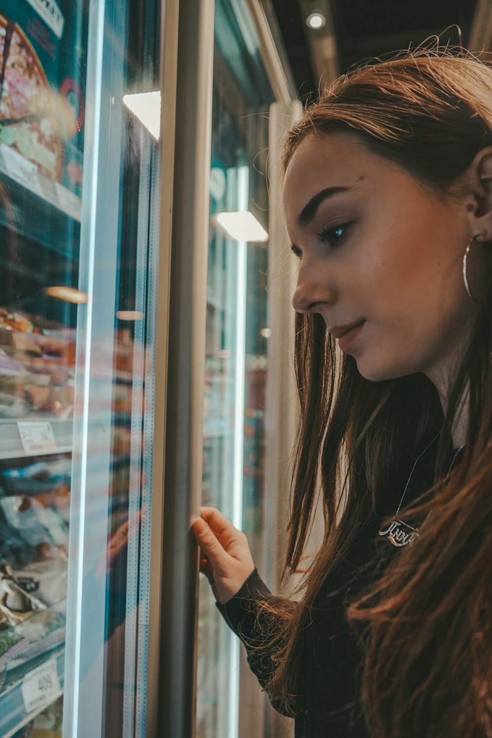 woman in brown leather jacket looking at the window