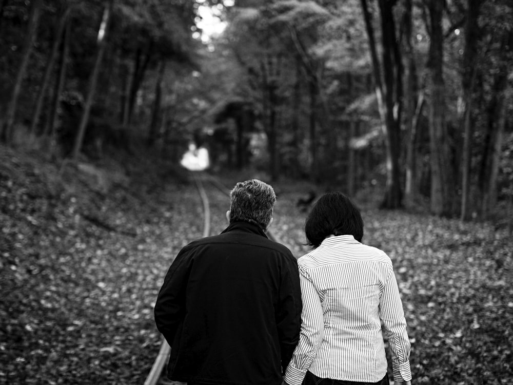 man and woman walking on forest during daytime