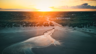 A serene landscape featuring a sunset over a clean beach.