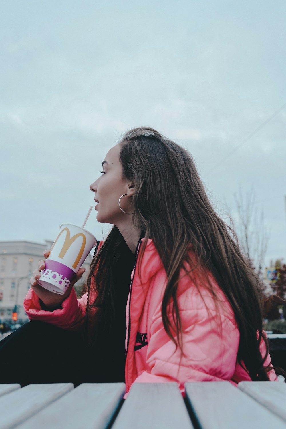 woman in red jacket drinking on white and red plastic cup