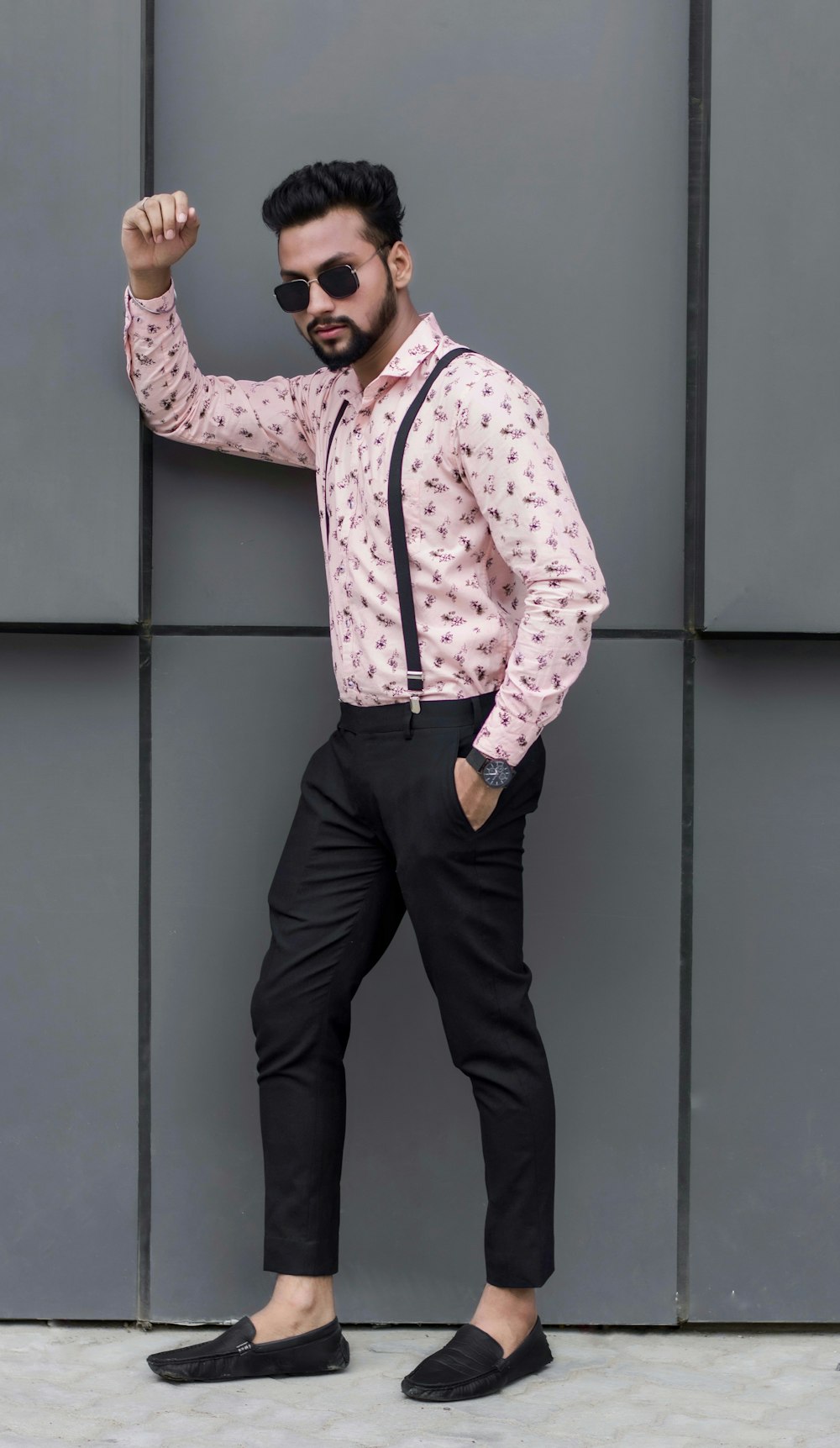 man in white and red checkered dress shirt and black pants standing beside gray wall