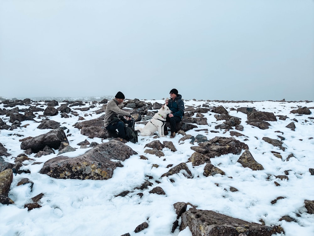people sitting on rock formation covered with snow during daytime