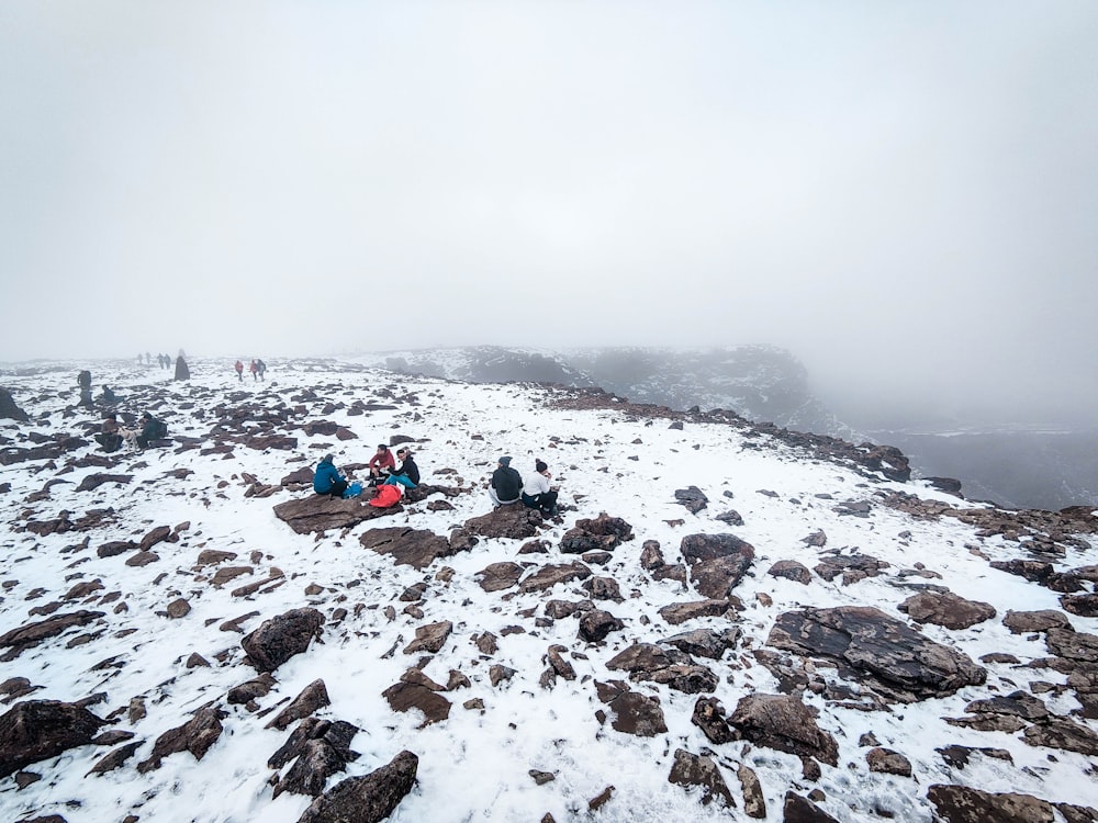 people sitting on snow covered ground during daytime