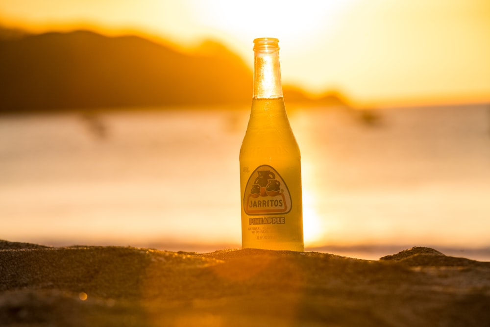 yellow labeled bottle on brown sand during sunset