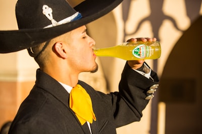 man in black hat drinking beer mariachi teams background