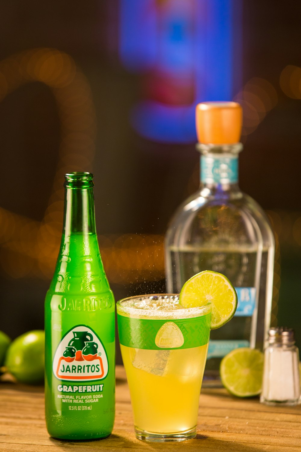 green glass bottle beside clear drinking glass with yellow liquid