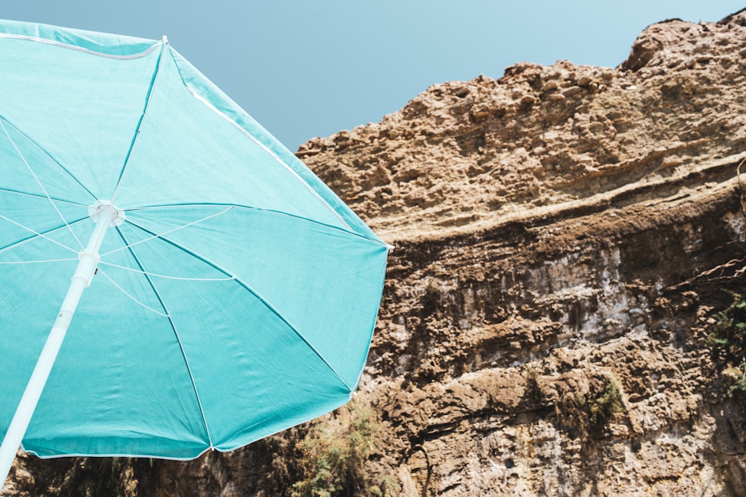 blue umbrella on rocky mountain during daytime