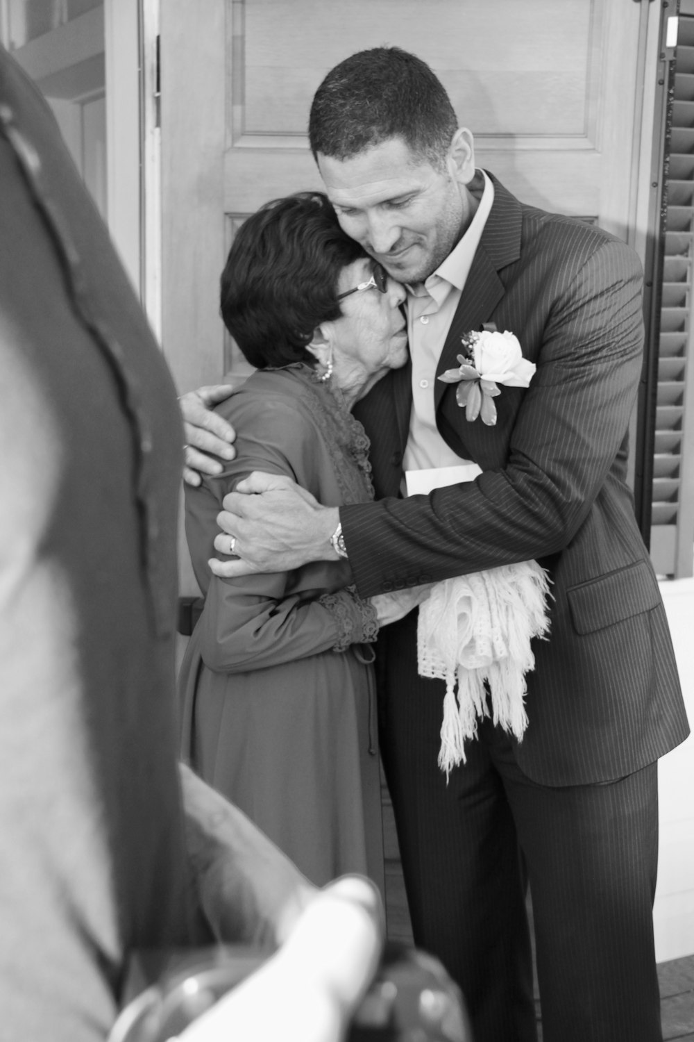 man in suit kissing woman in wedding dress in grayscale photography