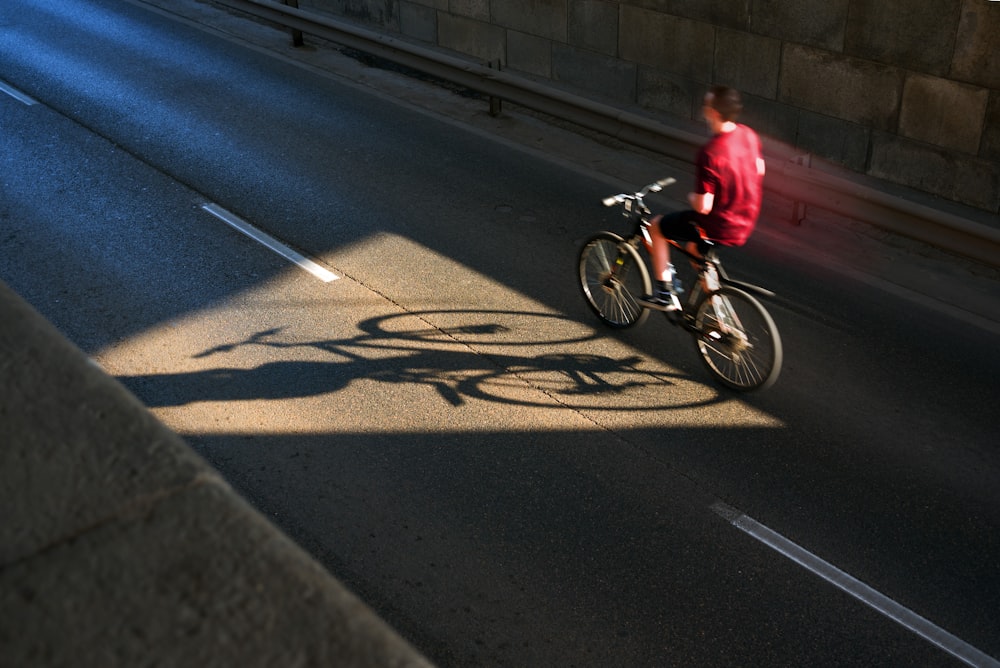 昼間、道路を自転車で走る赤いシャツを着た男性