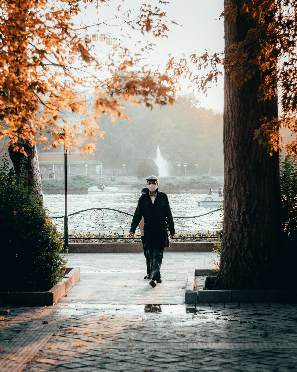 man in black coat standing on gray concrete floor near body of water during daytime