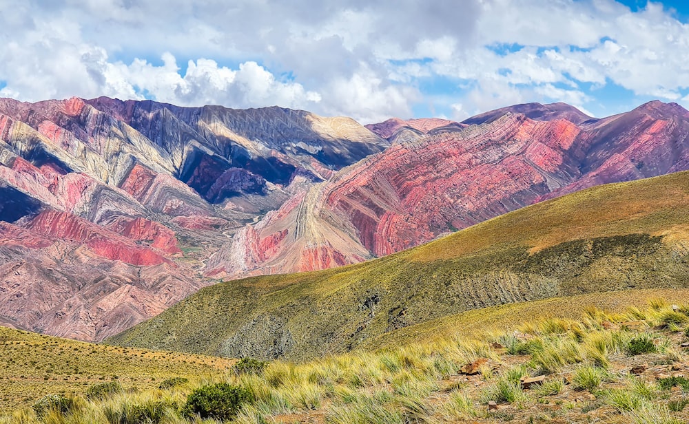 brown and green mountains under white clouds and blue sky during daytime